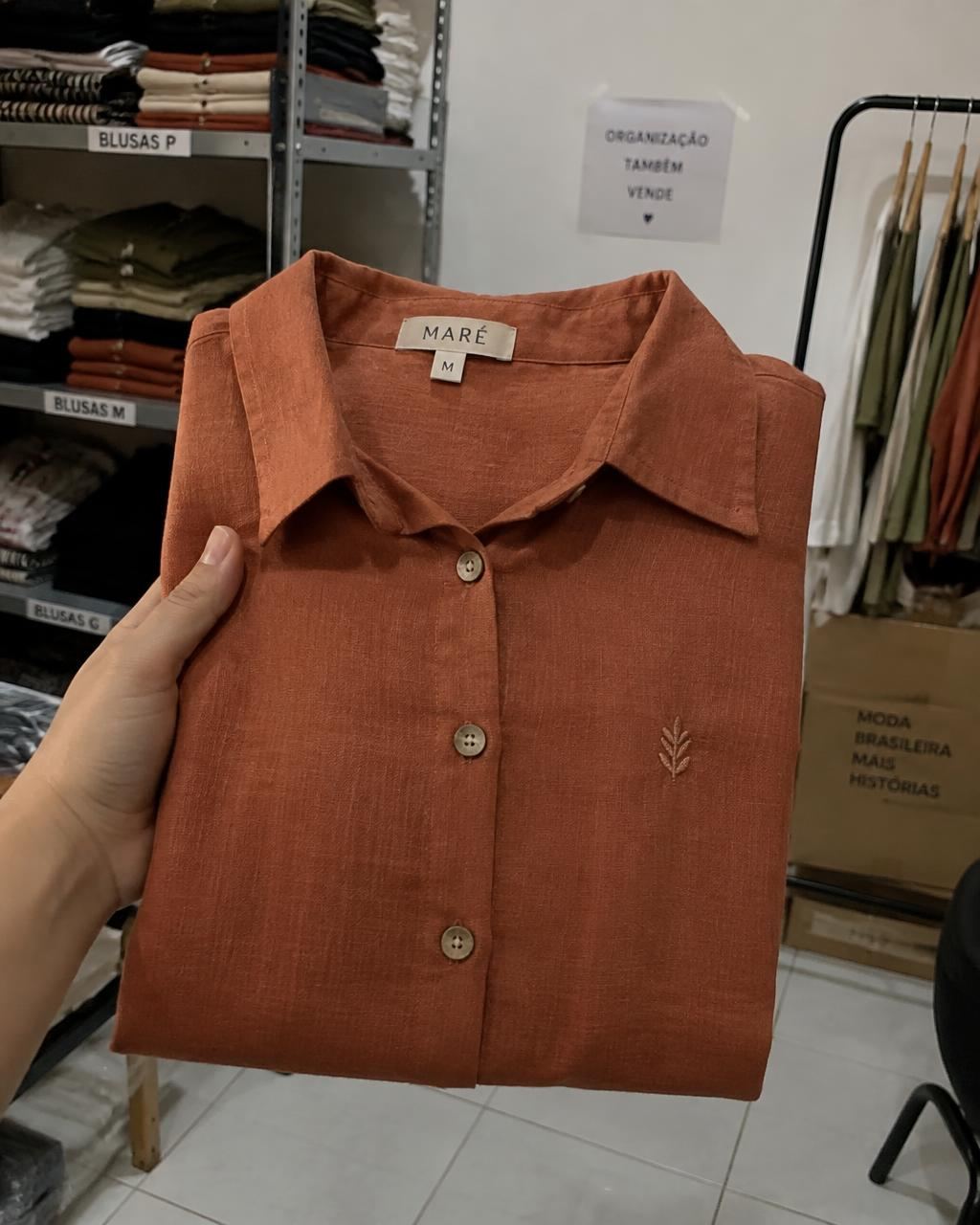 Foto de celular da camisa na mão, dentro da loja